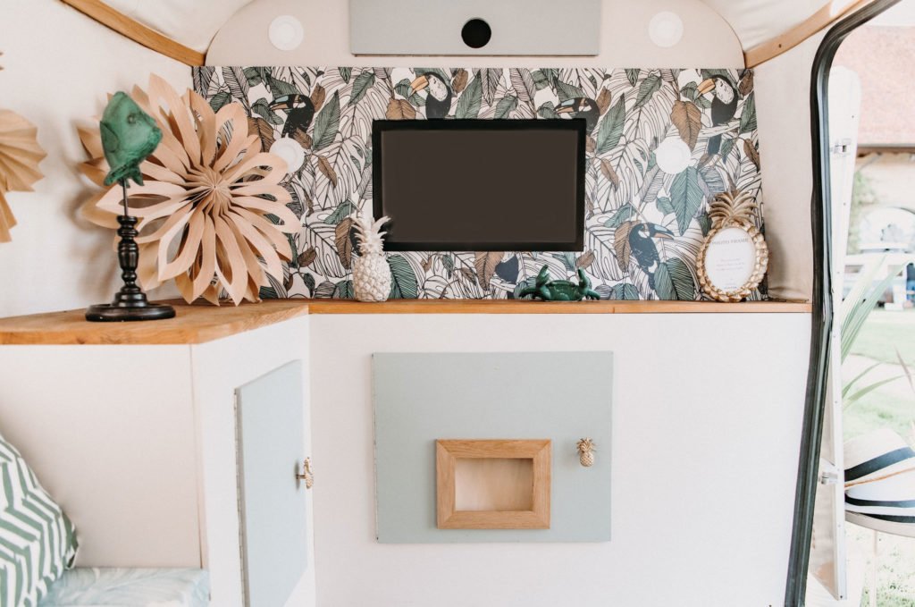 Intérieur de la caravane photobooth Virginia avec écran, décor fleuri et miroir en forme de soleil.